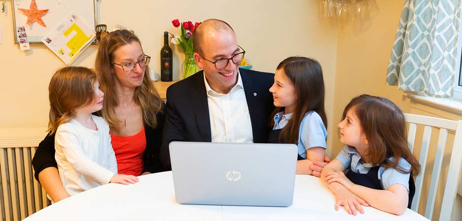 Des parents sourient devant un ordinateur avec leurs trois jeunes filles