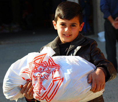 Un enfant rfugi irakien tenant un sac de nourriture portant le logo des Chevaliers de Colomb
